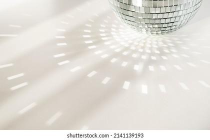Quả cầu disco trên nền trắng với bóng đổ và những tia sáng rực rỡ. Hiệu ứng chói và phản xạ ánh sáng. Sao chép không gian.