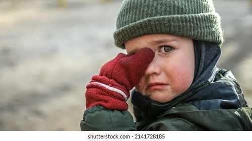 Kleine migrantenkind huilt. Portret van jongen jongen veegt tranen. Evacuatie kinderen. Oorlog Oekraïne