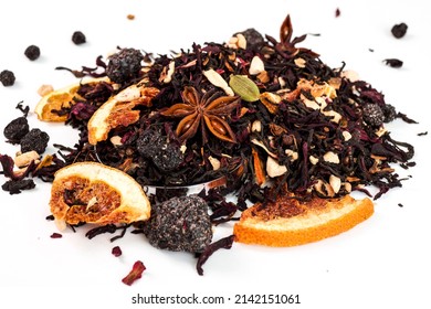 Daun teh terbuat dari bahan alami: daun hitam, kembang sepatu, kapulaga, jeruk kering. Tumpahan teh di atas meja. Konsep upacara minum teh. Teh merah dalam cangkir. Latar belakang putih.