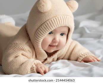 Simplemente hermosa. Una linda bebé sonriente. Una linda bebé de 3 meses en una cama boca abajo, con la cabeza en alto, mirándome con sus grandes ojos. Ropa beige cálida y esponjosa. Primer plano. Bebé de tres meses.