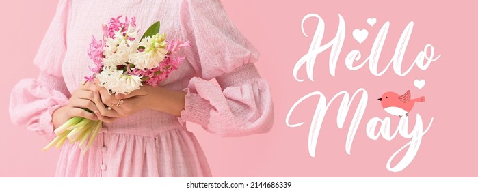 Schöne junge Frau mit Blumenstrauß und Text HALLO, MAI auf rosa Hintergrund