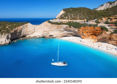 Vista aérea del mar azul, yate, roca, playa de arena con sombrillas en un día soleado en verano. Porto Katsiki, isla de Lefkada, Grecia. Hermoso paisaje con costa marina, barco, agua azul. Vista superior. Viaje