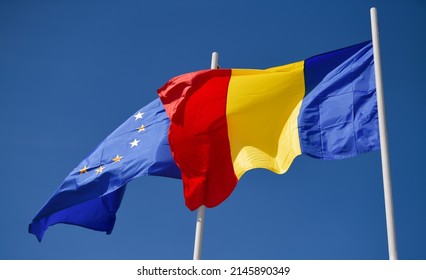 Vlaggen van Roemenië en de Europese Unie van de EU die tegen de blauwe hemelachtergrond kronkelen