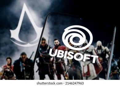 Kazan, Rusland - 15 apr 2022: Ubisoft is een Frans videogamebedrijf. Ubisoft-logo op smartphonescherm. Frame van Assassin Creed-franchisespel op achtergrond.