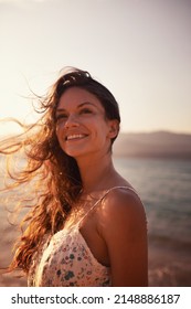 Enjoying the sea air. Cropped shot of a beautiful young woman on the beach.