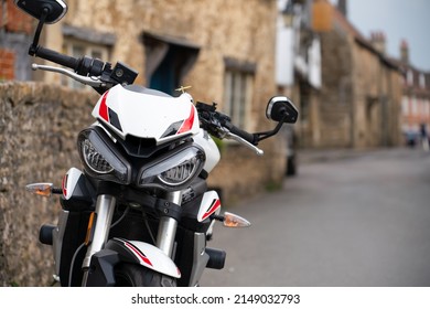 fehér triumph street triple S motorkerékpár parkolt egy 18. századi falu utcájában, Lacock Wiltshire