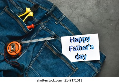 Zange, Schraubendreher und Maßband in der Jeanstasche und Karte mit Text Happy Fathers Day auf grauem Betonhintergrund. Geben Sie Papa ein Geschenk. Glückliches Vatertagskonzept. Flach liegen