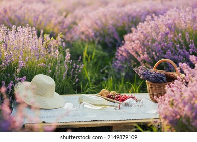 Picknick im Lavendelfeld mit Wein, Beeren und Croissants auf der Holzpalette. Weidenkorb mit Lavendelstrauß. Romantisches Picknick im Lavendelfeldhintergrund.