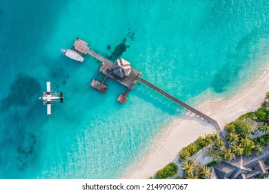 Wunderschöner Luftblick auf die Küste der Malediven, die Aussicht auf das Wasserflugzeug der Jetty Villa, das Holzboot Dhoni und den tropischen Strand. Palmen weißer Sand, Meer. Luxusreise- und Urlaubskonzept. Erstaunliche Luftlandschaft