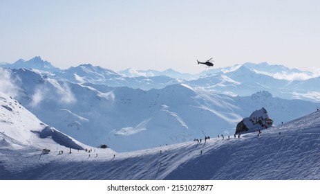 雪に覆われたスキー山の上を飛ぶヘリコプター