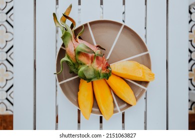 Fresh mango and dragon fruit on plate. Aesthetic minimalist photography.Tropical exotic fruits. Concept of a raw food diet, vegetarianism and replenishment of vitamins with tropical fruits. Flat lay