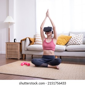 VRメガネをかけて床でヨガを練習する美しいアジアの女の子.学習技術オンラインスポーツクラスの使用.仮想現実、ゴーグル、学習.スポーツブラ運動瞑想を身に着けているセクシーな女性.
