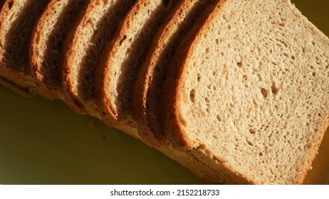 Top view close up of organic sliced bread isolated on green plate background. Bread slices spinning around slowly. Food background