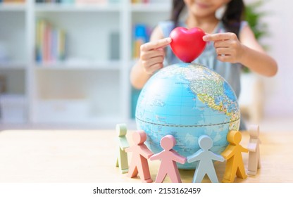 De handen van niet-geïdentificeerde kleine meisjes plaatsen het hart op de wereldbol rond met mensenmodel, concept van diversiteit, inclusie, eenheid, gelijkheid, vreedzaam, liefde, verbinding, vriendschap, saamhorigheid, red de aarde.