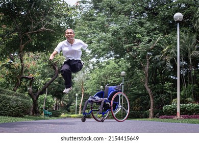 一名快乐男子在空中跳跃的图像。旁边有一辆轮椅。背景是一片模糊的绿树，充满积极的生活。