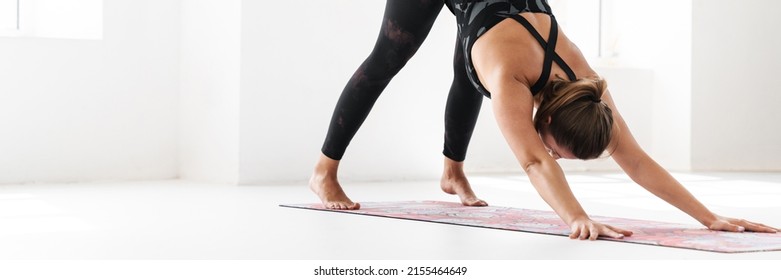 Jonge brunette blanke vrouw die yoga beoefent op een fitnessmat in de studio