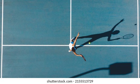 Vista aérea de la joven jugadora afroamericana que sirve en la cancha de tenis azul durante el día soleado. concepto de juego inalterado, deportivo, competitivo y de tenis.