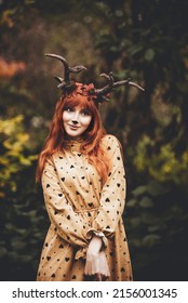 fairy woman with deer horns in autumn forest. Face painting. Beautiful mystery woman. redhead girl with big eyes magical sight