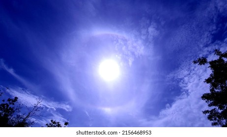 The morning sky in the beginning of the rainy season had the sun shining in a white circle around the bright blue sky. 