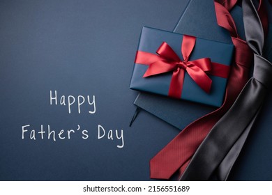 暗い青色の背景に青いギフト ボックス、ノート、ネクタイと幸せな父の日カード。