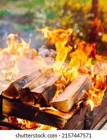 Fel brandende houten logboeken met gele hete vlammen van vuur. Sprankelend vreugdevuur in de grill op brandhout. Brandhout branden op grill. Haardvuur. Close-up bekijken met ondiepe DOF.