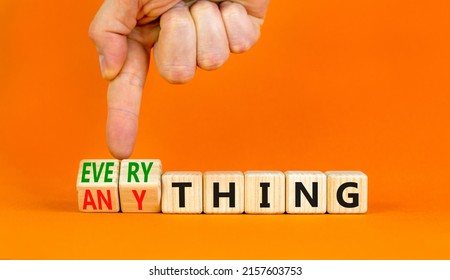 Anything or everything symbol. Businessman turns cubes, changes the concept word Anything to Everything. Beautiful orange background. Business motivational anything or everything concept. Copy space.