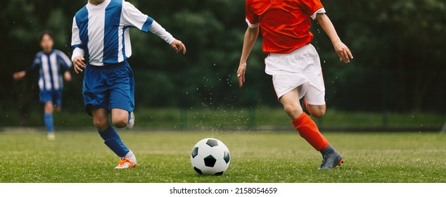 Los niños compiten en un partido de torneo en un duelo. Partido de fútbol en un día soleado de verano. Niños de la escuela con uniformes de camisetas azules y rojas corriendo con un balón de fútbol clásico en un campo de césped