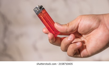 hand of man lighting cigarette lighter against bright background