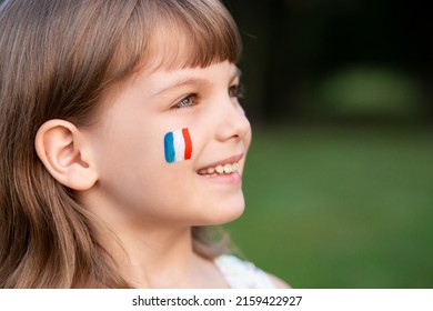 塗装されたフランス国旗を持つ子供のポートレート、クローズアップ。顔に描かれた青白赤旗の子供ファン。海外での教育。7 月 14 日、革命記念日、フランスの主要な祝日