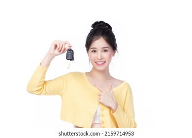 Hermosa joven asiática con camisa amarilla que se siente feliz y sonríe sosteniendo las llaves del camión con fondo blanco.