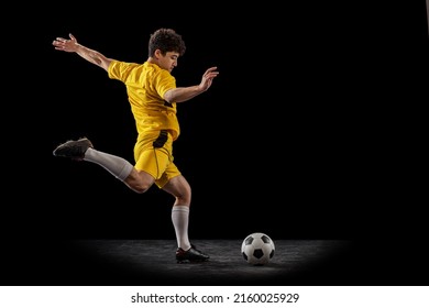 Retrato dinámico de fútbol profesional, entrenamiento de futbolistas con balón aislado en un fondo oscuro. Concepto de deporte, partido, anuncio, estilo de vida activo. Kit de fútbol amarillo brillante para deportistas.
