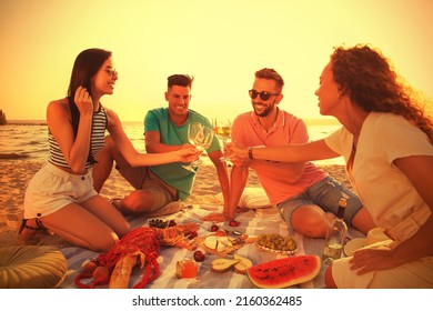 Group of friends having picnic outdoors at sunset