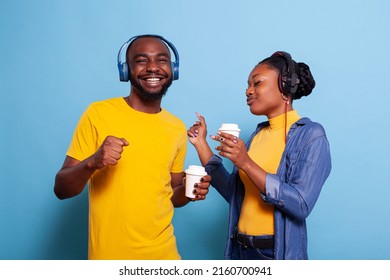 Joyful people dancing and listening to music on headphones, doing funny dance moves on camera. Romantic man and woman having fun with mp3 song on headphones. Couple with audio laughing.
