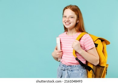 Kleine intelligente glückliche Schülerin rothaariges Mädchen 12-13 Jahre alt in rosa gestreiftem T-Shirt halten Notizbuchbuch gelber Schultaschenrucksack isoliert auf pastellblauem Hintergrund Kinder Lifestyle Kindheit Konzept
