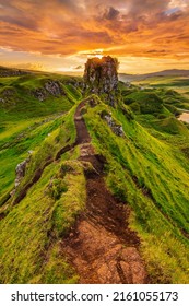 Camino de arena hasta la cima de una roca Castle Ewen en la Isla de Skye. Puesta de sol en verano de un paisaje en Escocia por la noche con nubes en el cielo. Prados verdes con colinas y un lago