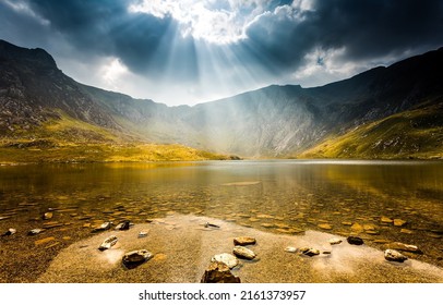 山の湖の雲の切れ間から太陽が差し込む。山の湖の風景の上に雲を突き破る太陽。山の湖の風景。山の湖