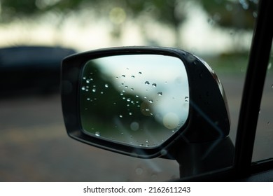Gotas de rocío en el espejo lateral de un automóvil que refleja el cielo y los árboles