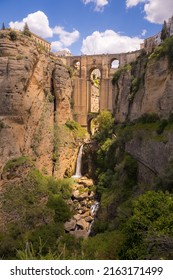 Widok na stary kamienny most nad kanionem i wodospadem w Rondzie w Hiszpanii; przy moście Puente Nuevo, łuku, Andaluzja, Hiszpania