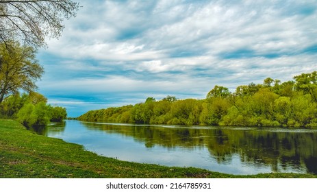 流れる川とふわふわの雲が美しい春の緑の風景。春の美しい自然。無人。曇り空のある夏の風景の写真。