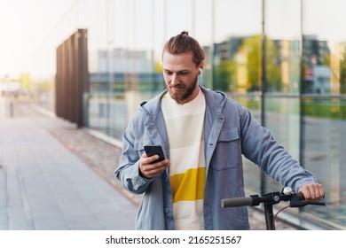 Anak muda dengan e-skuter menggunakan aplikasi sistem berbagi skuter di smartphone