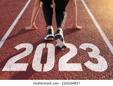 Rear view of a woman preparing to start on an athletics track engraved with the year 2023