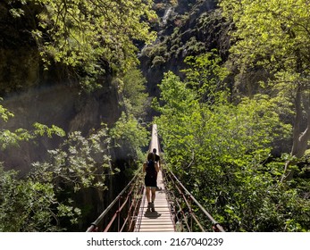 Eventyrlystne mennesker går på en hængebro, mens de nyder en vandretur i bjergene. Rejser, aktiv livsstil og eventyrkoncept.
