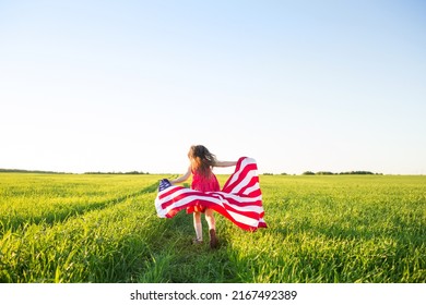 Hari Kemerdekaan AS atau Hari Peringatan. latar belakang patriotik dengan ruang fotokopi. gadis kecil dengan bendera Amerika berlari melintasi lapangan di alam