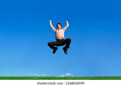 An energetic senior man jumping against blue sky
