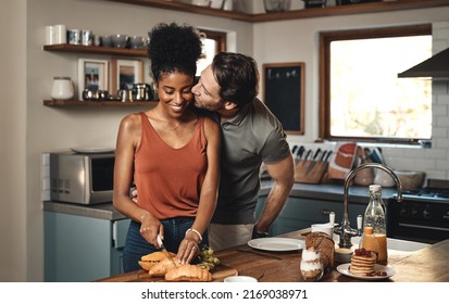 Theres no way Im skipping breakfast with you. Shot of a man kissing his wife while she prepares breakfast in the kitchen at home.