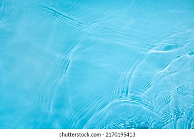 Transparante blauwe heldere wateroppervlaktetextuur met rimpelingen, spatten en bubbels. Abstracte aardachtergrond Watergolven in zonlicht. Cosmetische moisturizer micellaire toneremulsie. Bovenaanzicht, kopieer ruimte