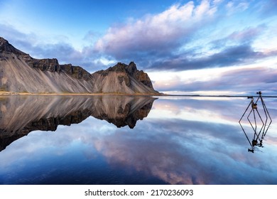 Vestrahorn-gebergte weerspiegeld in ondiep water, Zuid-IJsland. Twee statieven zijn ingesteld om foto's te maken van deze perfecte spiegelreflectie.