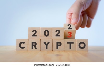暗号通貨の株式市場のコンセプト。2023 年のデジタル取引所での取引。仮想通貨の概念。マイニングまたはブロックチェーン技術。手は、木製の立方体のテキスト暗号 2021 から 2022 を背景に反転させます。
