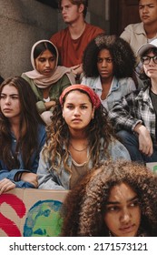 Ativistas climáticos multiculturais sentados do lado de fora de um prédio com cartazes e faixas. Grupo de manifestantes adolescentes protestando contra o aquecimento global e as mudanças climáticas.