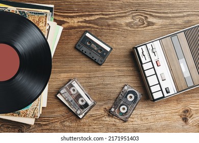 Bản ghi vinyl, băng cassette và máy ghi âm trên bàn gỗ. Phong cách âm nhạc retro. Bữa tiệc âm nhạc thập niên 80. Phong cách cổ điển. Thiết bị tương tự. Âm thanh nổi. Trở về quá khứ